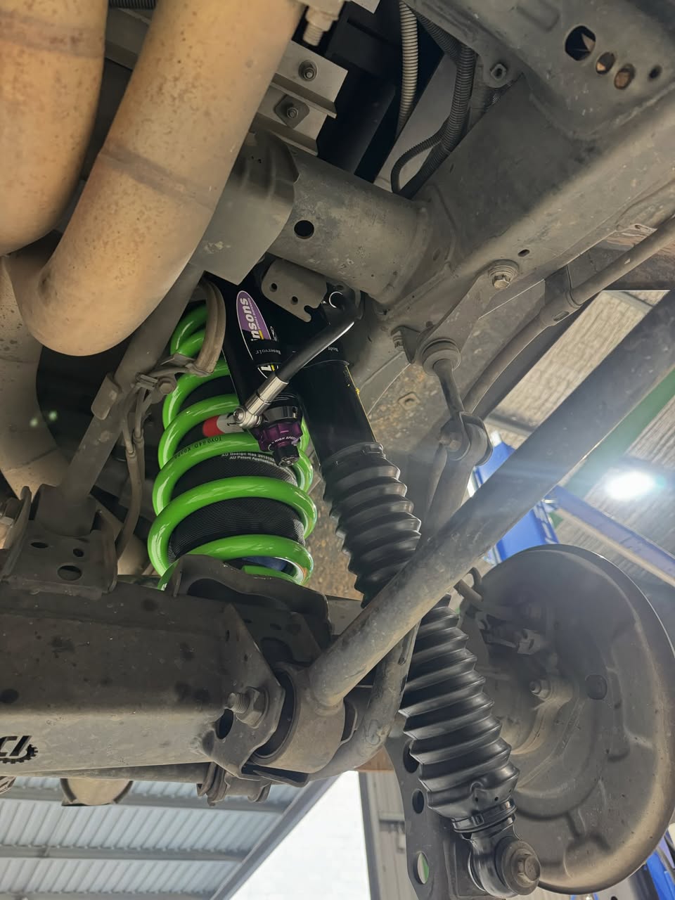 A green coil spring and shock absorber fitted under a four wheel drive